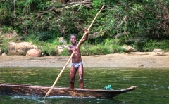 A local afro-ecuadorian boy poses while paddling a traditional canoe carved from a single tree on the Wimbi River, northwest Ecuador.