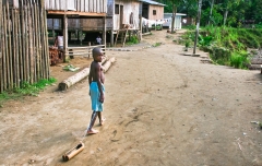 A young afro-ecuadorian boy pulls his toy canoe through the town of Playa de Oro, Ecuador.