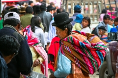 A local Bolivian woman in a traditional bowler hat and vibrant cloth weaving in the town of Sorata, Bolivia.