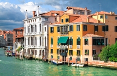 Large buildings sit above deep green water on a stormy day in Venice, Italy.